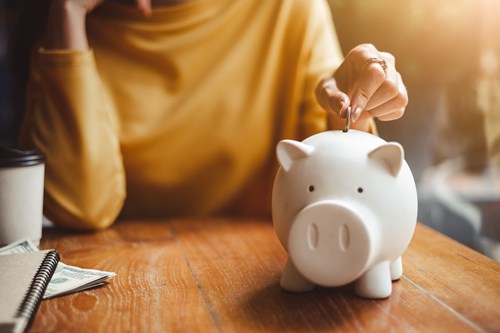 Woman placing a coin into a piggy bank.