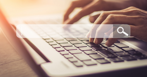 Person typing on a laptop keyboard in the background with a search input field box.