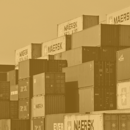 Stacks of shipping containers. Image has a yellow tint.