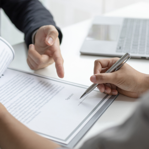 A person signing a contract with a pen.