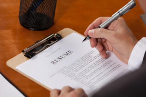 Man writing on a clipboard with a resume