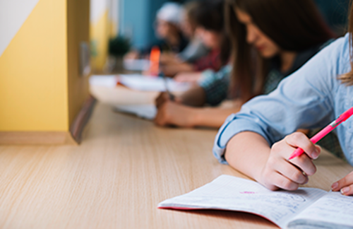 A close up view of a student writing in their exercise book.