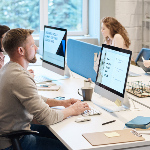 Group of people sitting at a desk working on computers.