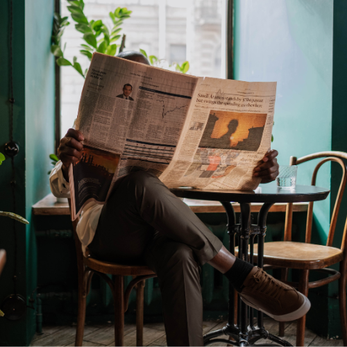 Man reading a newspaper. Image has a yellow tint.