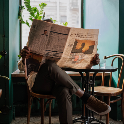 Person sitting in a chair reading a newspaper.