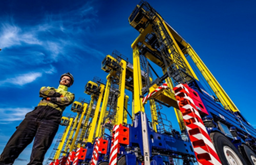 Straddle carrier driver standing with arms crossed