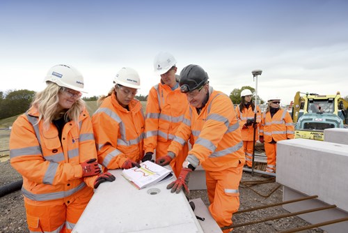 Construction workers standing outside on a building site looking at plans.