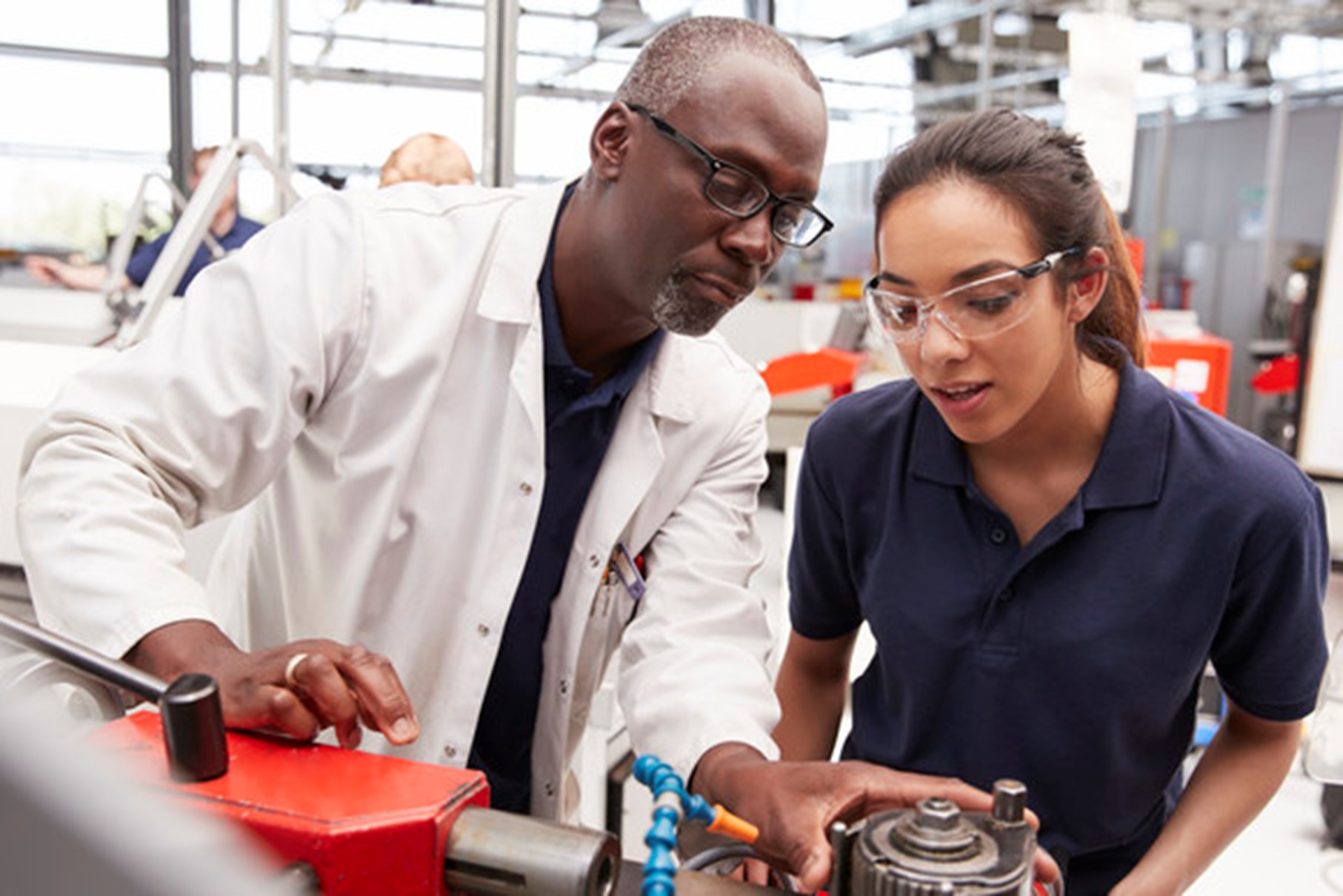 Engineer showing equipment to a female apprentice, close up.