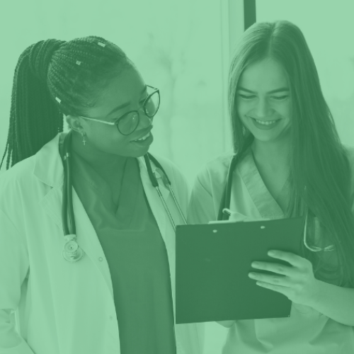 Two nurses smiling and looking at a clipboard. Image has a green tint.