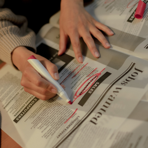 Person circling a job advert in a newspaper with a red marker