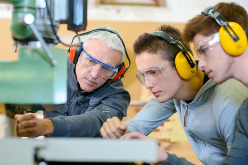 Instructor using tools with woodworking and construction apprentices watching.